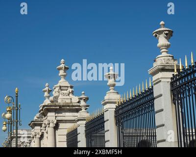 Section d'un mur historique avec des décorations dorées et une clôture en fer forgé sous un ciel bleu, Madrid, Espagne Banque D'Images