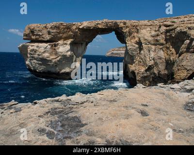 Arc rocheux naturel sur une côte accidentée avec une mer sauvage ci-dessous et un ciel bleu clair au-dessus, gozo, mer méditerranée, malte Banque D'Images