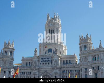 Un grand bâtiment avec des détails gothiques et une bannière. Drapeaux espagnols agitant devant un ciel bleu, Madrid, Espagne Banque D'Images