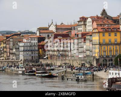 Vue côtière d'une ville avec des bâtiments colorés, rivière, bateaux et gens sur la rive, Porto, Douro, Portugal Banque D'Images