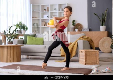 Petite fille avec balle faisant de la gymnastique à la maison Banque D'Images