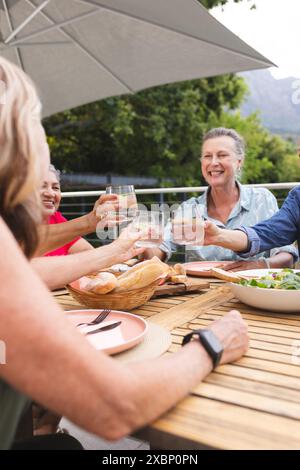 Groupe de femmes âgées diverses appréciant des boissons ensemble à la table extérieure Banque D'Images