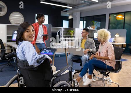 Divers collègues d'affaires dans la réunion de bureau ; femme en fauteuil roulant avec tablette ; effort de démarrage Banque D'Images