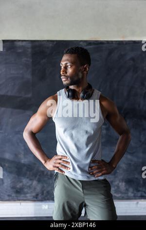 Homme afro-américain fort et en forme debout avec confiance avec des écouteurs après l'entraînement Banque D'Images