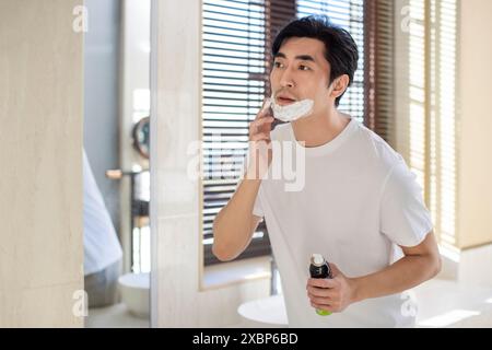 Homme mûr dans le rasage de salle de bain Banque D'Images