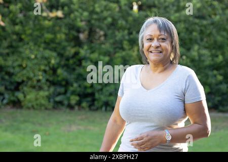 Femme senior biraciale souriant à l'extérieur dans une tenue décontractée, espace de copie Banque D'Images