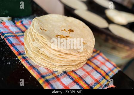 Un tas de tortillas fraîchement préparées est vu placé sur un tissu dans un tortillería à Morelia, Michoacán, Mexique. Banque D'Images