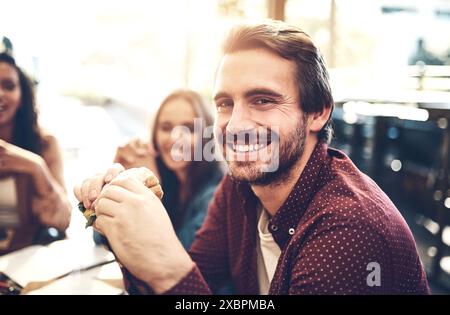 Déjeuner d'affaires, portrait et sandwich avec homme designer au restaurant pour collaboration ou réunion. Visage, heureux et sourire de l'employé créatif dans le café Banque D'Images