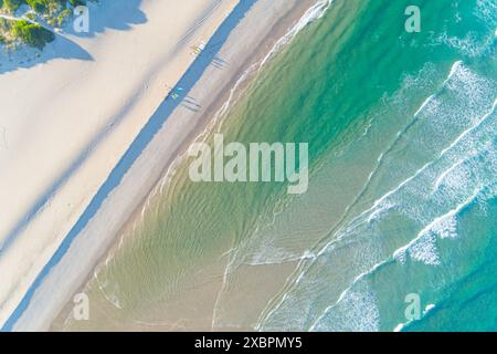 groupe de surfeurs sur le rivage d'une plage à l'aube vu d'un drone Banque D'Images