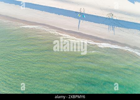 groupe de surfeurs sur le rivage d'une plage au lever du soleil vu d'un drone Banque D'Images