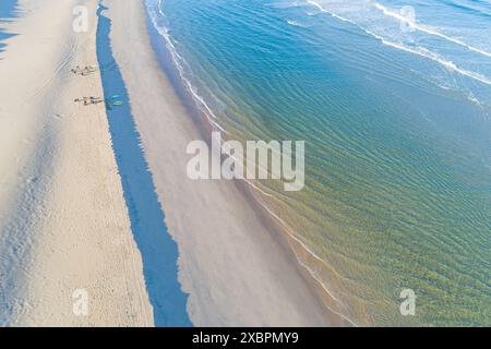 surfeurs sur le rivage d'une plage au lever du soleil vu d'un drone Banque D'Images