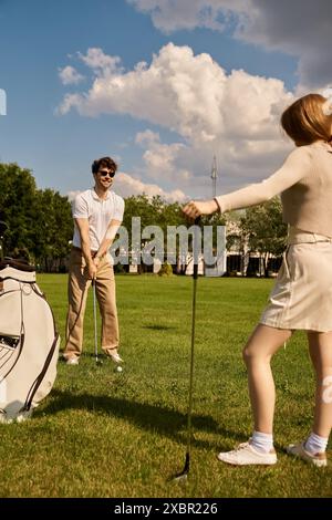 Un jeune couple habillé élégamment jouant au golf ensemble dans un parc, profitant d'une journée tranquille à l'extérieur. Banque D'Images