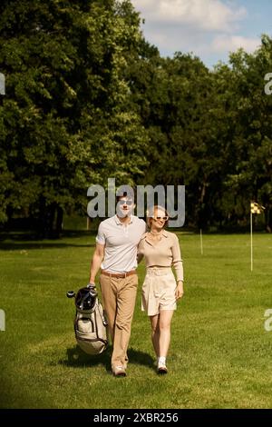 Un jeune couple gracieux dans une tenue élégante profitant d'une promenade tranquille sur un parcours de golf pittoresque entouré d'une végétation luxuriante. Banque D'Images