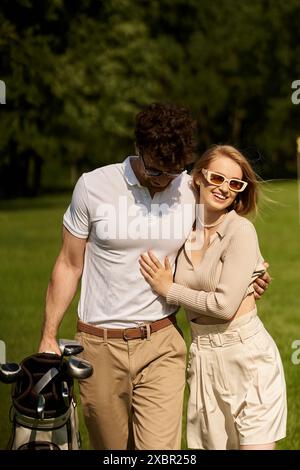 Un jeune homme et une femme élégants se tiennent proches les uns des autres sur un parcours de golf verdoyant, dégageant élégance et sophistication. Banque D'Images