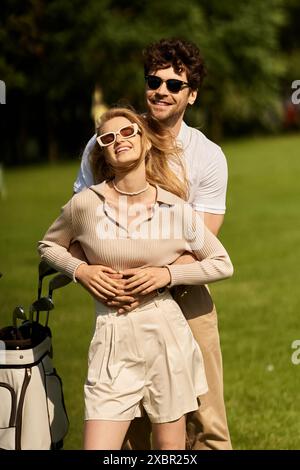 Un jeune couple élégant embrasse passionnément sur un parcours de golf verdoyant, incarnant luxe et romantisme dans un cadre idyllique. Banque D'Images