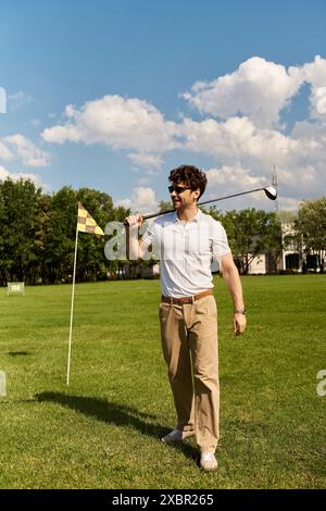 Un homme en tenue élégante joue au golf sur un terrain verdoyant, incarnant le style classique des loisirs de classe supérieure. Banque D'Images