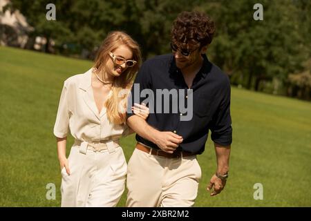 Un beau jeune couple, habillé élégamment, se promenant tranquillement dans un parc sur un terrain verdoyant. Banque D'Images