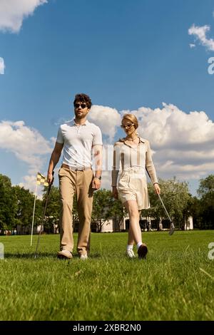 Un jeune homme et une jeune femme en tenue élégante marchent ensemble sur un parcours de golf verdoyant, profitant d'une activité de plein air haut de gamme. Banque D'Images