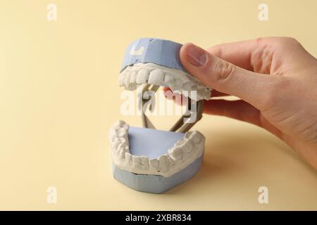 Femme tenant le modèle dentaire avec des gencives sur fond jaune, gros plan. Fonte de dents Banque D'Images