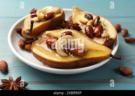 Délicieuses poires cuites au four avec des noix, des étoiles d'anis et du miel sur une table en bois bleu clair, gros plan Banque D'Images