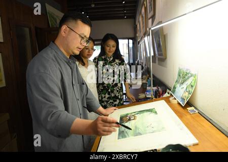 (240613) -- HANGZHOU, 13 juin 2024 (Xinhua) -- L'artiste Zhang Tiantian travaille sur une aquarelle représentant une scène le long du Grand canal dans un studio de Xiaohezhi Street, bloc historique et culturel le long du Grand canal à Hangzhou, province du Zhejiang de l'est de la Chine, 12 juin 2024. Avec une histoire de plus de 2 500 ans, le Grand canal, reliant Pékin et Hangzhou dans la province du Zhejiang de l'est de la Chine, a servi d'artère de transport importante dans la Chine ancienne. Le canal a été classé au patrimoine mondial de l'UNESCO en Chine en juin 2014. Ces dernières années, les autorités locales ont établi des priorités Banque D'Images