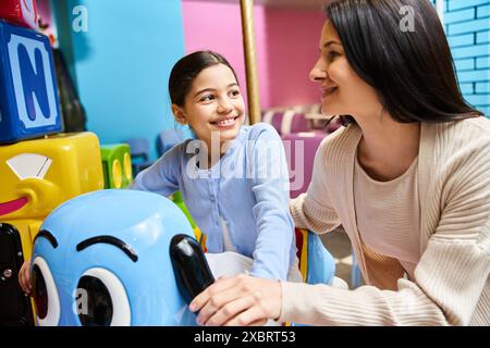 Une mère et sa fille s'engagent joyeusement dans le jeu avec des jouets dans une zone de jeu animée de magasins de jouets sur un week-end. Banque D'Images