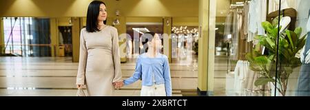 Une femme et un enfant marchant joyeusement dans un centre commercial animé, partageant un moment de liaison au milieu de la frénésie du shopping. Banque D'Images