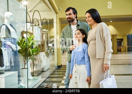 Une famille joyeuse parcourt les vêtements dans un centre commercial animé lors d'une sortie shopping amusante. Banque D'Images