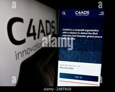 Personne tenant un téléphone portable avec la page Web du Centre pour les études avancées de défense (C4ADS) devant le logo. Concentrez-vous sur le centre de l'écran du téléphone. Banque D'Images