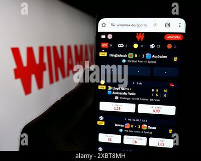 Personne tenant un smartphone avec la page web de la société française de Paris sportifs Winamax sa devant le logo de l'entreprise. Concentrez-vous sur le centre de l'écran du téléphone. Banque D'Images