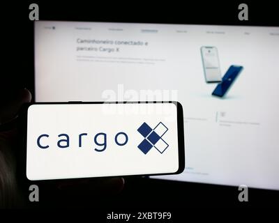 Personne tenant un smartphone avec le logo de la société brésilienne de plate-forme logistique CargoX en face du site Web. Concentrez-vous sur l'affichage du téléphone. Banque D'Images