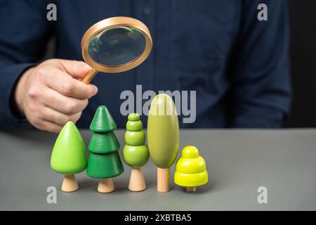 Un homme tient une loupe sur des arbres et des buissons. Concept d'évaluation du climat et de l'air. Science de la recherche végétale. Installations d'inspection. Nature éco Banque D'Images