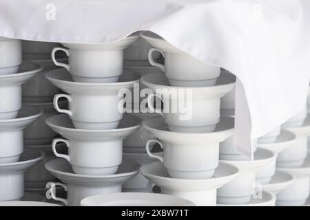 Des tasses à thé vides et des soucoupes blanches sont sur la table recouverte d'une nappe blanche dans un restaurant Banque D'Images