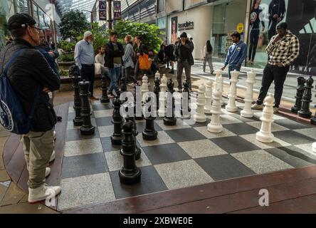 Les gens jouant aux échecs avec de grandes pièces sur le sol à l'extérieur du centre commercial Westfield à Stratford, Londres, Angleterre, Royaume-Uni Banque D'Images