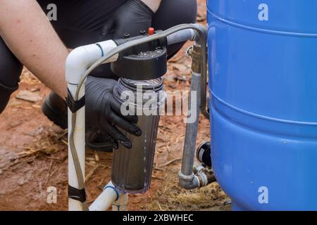 Le travailleur effectuant l'entretien remplace le filtre à l'installation de traitement de l'eau domestique Banque D'Images