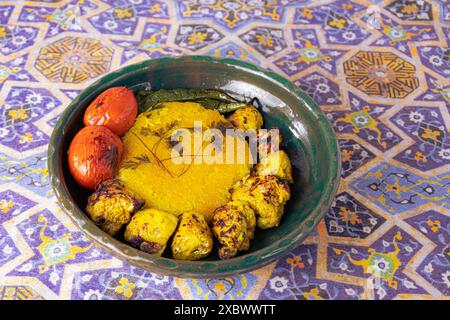 Kebab au poulet de style persan avec riz au safran, piments grillés et tomates dans un bol en argile verte, sur un fond de panier traditionnel iranien Banque D'Images