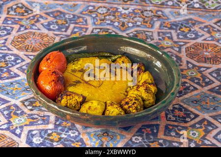 Kebab au poulet de style persan avec riz au safran, piments grillés et tomates dans un bol en argile verte, sur un fond de panier traditionnel iranien Banque D'Images