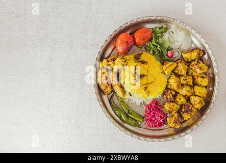 Le plat iranien populaire se compose de poulet kebab avec riz safran, piments grillés et tomates, oignons, basilic, radis et chou rouge mariné Banque D'Images