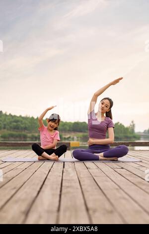 Maman et fille chinoises faisant du yoga dans Un parc Banque D'Images