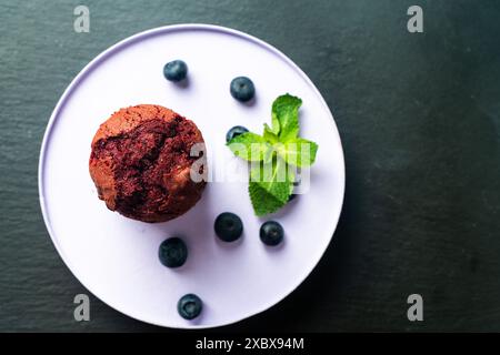 Muffin aux myrtilles maison avec myrtilles et menthe sur une assiette légère sur mica noir. Photo de haute qualité Banque D'Images