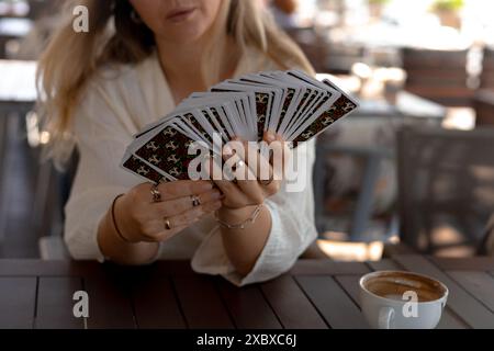 Femme dans une tenue légère lit des cartes de Tarot sur une table dans un café Banque D'Images