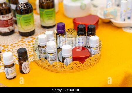 Osijek/ Croatie - 7 06 2024 : salon de la santé et de la beauté. assortiment de bouteilles d'huile essentielle sont affichés sur un plateau doré avec un bord festonné. La bouteille Banque D'Images