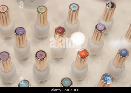 Osijek/ Croatie - 7 06 2024 : salon de la santé et de la beauté. variété de bouteilles de vernis à ongles avec différents bouchons de couleur sont affichés sur une surface blanche. Le bo Banque D'Images