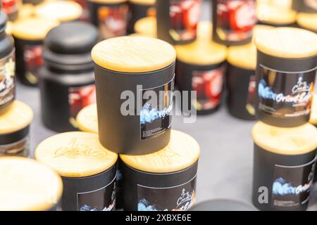 Osijek/ Croatie - 7 06 2024 : salon de la santé et de la beauté. assortiment de bougies parfumées noires avec couvercles en bois sont affichés sur une table de stalle de marché. Le c Banque D'Images