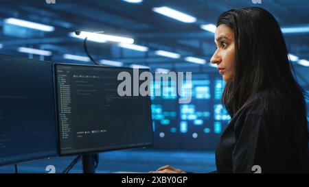 Ingénieur méticuleux inspectant les rangées de serveurs opérationnels dans le centre de données de sécurité de réseau informatique. Femme supervisant des superordinateurs fournissant des ressources de traitement et de mémoire pour diverses charges de travail Banque D'Images