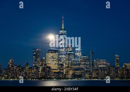 Horizon de Manhattan vu de Hoboken, New Jersey, au crépuscule, avec la lune derrière quelques nuages. Banque D'Images