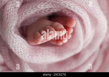 Pied de bébé sur couvre-lit souple rose, couverture. Détail des jambes d'un nouveau-né. Banque D'Images