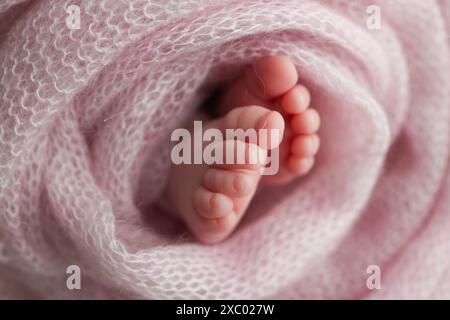 Pied de bébé sur couvre-lit souple rose, couverture. Détail des jambes d'un nouveau-né. Banque D'Images