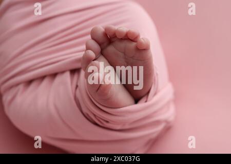 Pied de bébé sur couvre-lit souple rose, couverture. Détail des jambes d'un nouveau-né. Banque D'Images