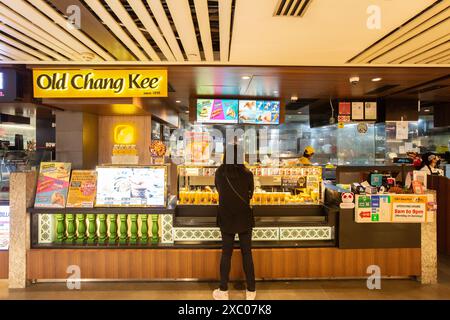 Une cliente commande du curry puff au magasin Old Chang Kee. Singapour. Banque D'Images